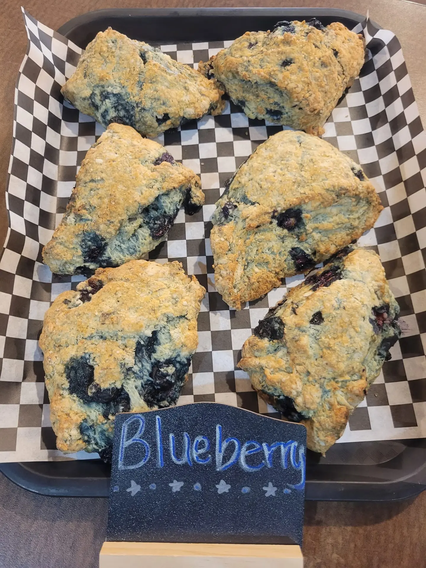Tray of blueberry scones with a chalkboard sign at a bakery in Lead, SD